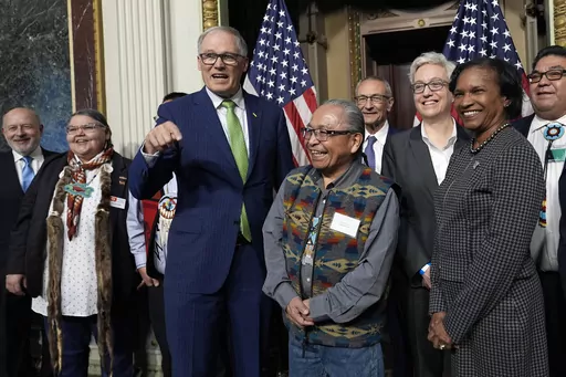 Washington Gov. Jay Inslee, third from left, stands with Chair Gerry Lewis of the Yakama Nation, fourth from left, as they and others pose for a photo following a ceremonial signing ceremony in Washington, Friday, Feb. 23, 2024. The ceremonial signing is an agreement between the Biden administration and state and Tribal governments to work together to protect salmon and other native fish, honor obligations to Tribal nations, and recognize the important services the Columbia River System provides