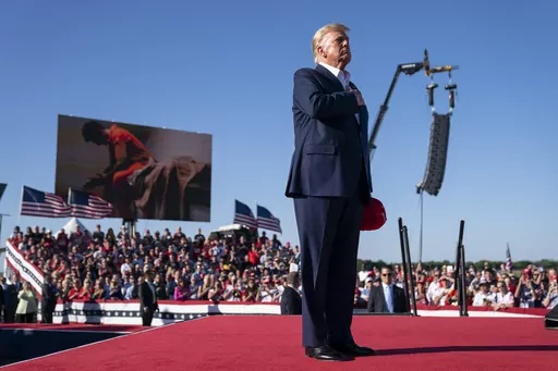 Former President Donald Trump stands while a song, "Justice for All," is played during a campaign rally at Waco Regional Airport, March 25, 2023, in Waco, Texas. The song features a choir of men imprisoned for their role in the Jan. 6, 2021, insurrection at the U.S. Capitol singing the national anthem and a recording of Trump reciting the Pledge of Allegiance. (AP Photo/Evan Vucci)