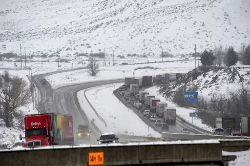 A truck delivering food to Reno, Nev., is seen heading east on I-80 as traffic heading west gets backed up as it approaches a chain control checkpoint near Verdi, Nev., Wednesday, Dec. 29, 2021. More snow and rain fell on California on Wednesday, causing travel disruptions on mountain routes and raising the risk of debris flows from wildfire burn scars. Major highways through the snow-blanketed Sierra Nevada remained open, but chain requirements were in effect in many areas. (Jason Bean/The Reno