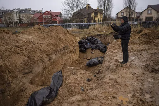 A journalist takes video of a mass grave in Bucha, on the outskirts of Kyiv, Ukraine, Sunday, April 3, 2022. Ukrainian leaders have encouraged journalists to document what is happening in the country. (AP Photo/Rodrigo Abd, File)