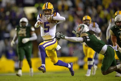LSU quarterback Jayden Daniels (5) runs past UAB safety Keondre Swoopes (0) during the first half an NCAA college football game in Baton Rouge, La., Saturday, Nov. 19, 2022. (AP Photo/Matthew Hinton)