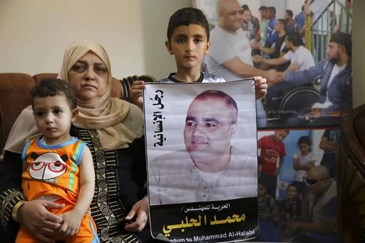 Amal el-Halabi holds her grandson Fares while her grandson Amro, 7, holds a picture of his father Mohammed el-Halabi, Gaza director of the international charity World Vision, who is detained and accused by Israeli security of diverting sums to Hamas that exceed its total budget, at his family house in Gaza City, Aug. 8, 2016. In May 2022, nearly six years after Israel accused Mohammed el-Halabi of diverting tens of millions of dollars from an international charity to Gaza's militant Hamas rulers