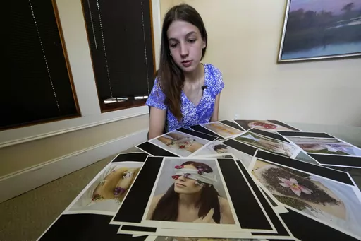 Gabrielle Jameson, a victim of a sexual assault, looks over photographs from her college thesis project, which she describes as part of her healing process, at the office of her attorney Tony Le Mon, in Covington, La., Tuesday, June 6, 2023. Jameson, who watched the man who coerced her into a sex act when she was 16 walk free in a plea deal, lost a legal battle, Tuesday, June 27, to sue the prosecutor in the case. (AP Photo/Gerald Herbert, File)