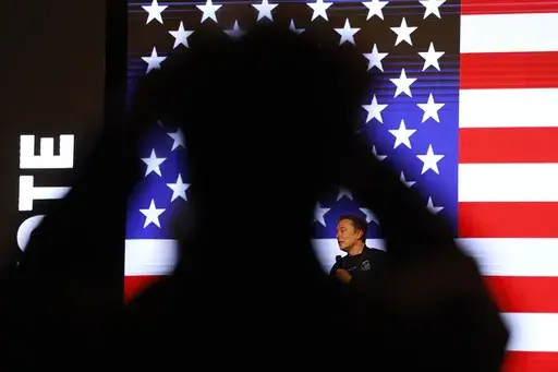 People listen to Elon Musk during a town hall Sunday, March 30, 2025, in Green Bay, Wis. (AP Photo/Jeffrey Phelps)