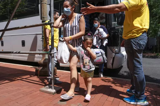 Silvia Moreno del Castillo, center, of Lima, Peru, holds her daughter Brisa, 3, by the hand, followed by her husband Gerardo Puente, as the family who is seeking asylum from Peru is greeted by Derick Alegria, left, and Orlando Andara, both with the nonprofit SAMU First Response, as a bus of asylum seekers who were sent from Arizona to Washington arrives, Aug. 11, 2022, to a church on Capitol Hill in Washington. A coalition of conservative-leaning states are making a last-ditch effort to keep in 