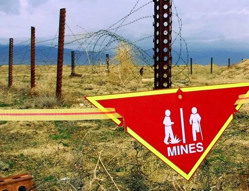 An international sign warning about mines hangs beside a minefield at Bagram Air Base on, March 22, 2002. The White House announced Tuesday a new policy curtailing the use of anti-personnel land mines by the U.S. military, reversing a more permissive stance that was enacted by former President Donald Trump. Under the policy, such explosives will still be allowed to defend South Korea against a potential attack by North Korea, but otherwise they will be banned.  (AP Photo/Mikhail Metzel, File)