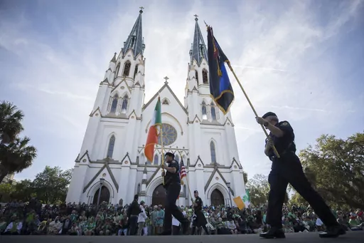 Participants carry flags past the Cathedral Basilica of St. John the Baptist while marching in the St. Patrick's Day parade, March 17, 2023, in historic downtown Savannah, Ga. Savannah, Georgia's oldest city, is planning a supersized celebration as it marks the 200th anniversary of its beloved St. Patrick's Day parade. City Manager Jay Melder says he's expecting historic crowds for the Irish-themed parade Saturday, March 16, 2024. (AP Photo/Stephen B. Morton)