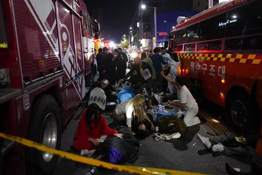 Injuried people are helped at the street near the scene in Seoul, South Korea, early Sunday, Oct. 30, 2022. South Korean officials said around 50 people were in cardiac arrest and a number feared dead after being crushed by a large crowd pushing forward on a narrow street during Halloween festivities in the capital Seoul. (AP Photo/Lee Jin-man)