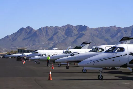A Scottsdale Airport staffer waits on a private jet, as the airport gears up for the expected dramactic increase in private jet traffic, leading up to the NFL Super Bowl LVII football game at Scottsdale Airport in Scottsdale, Ariz., Thursday, Feb. 2, 2023. (AP Photo/Ross D. Franklin)
