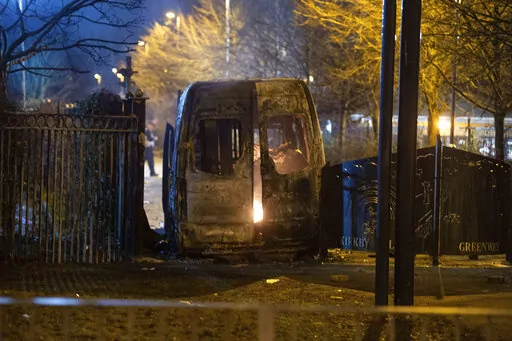 A burnt out police van after a demonstration outside the Suites Hotel in Knowsley, Merseyside, where people were protesting against asylum seekers staying at the hotel, in Knowsley, England, Friday, Feb. 10, 2023. An anti-migration protest outside a hotel housing asylum-seekers in northwest England turned violent and resulted in the arrests of 15 people, local police said. Merseyside Police department said Saturday that a police officer and two civilians sustained minor injuries during the Frida