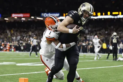 New Orleans Saints tight end Taysom Hill (7) scores as Cleveland Browns safety Juan Thornhill (1) defends in the first half of an NFL football game in New Orleans, Sunday, Nov. 17, 2024. (AP Photo/Butch Dill)