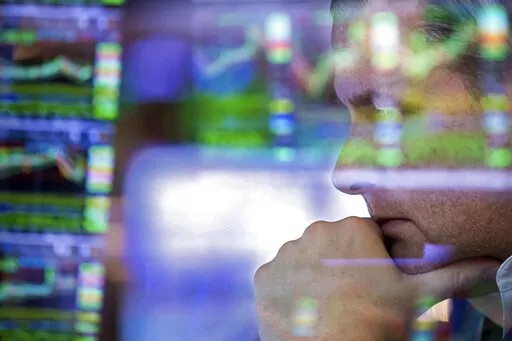In this photo provided by the New York Stock Exchange, specialist Gregg Maloney works at his post on the trading floor, Friday, March 11, 2022. Stocks are wavering between gains and losses on Wall Street Friday, as uncertainty about the war in Ukraine and inflation continues to knock markets around.(Allie Joseph/New York Stock Exchange via AP)