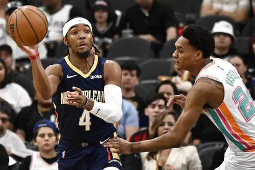 New Orleans Pelicans' Devonte' Graham (4) looks to pass as he is defended by San Antonio Spurs' Devin Vassell during the first half of an NBA basketball game on Friday, March 18, 2022, in San Antonio. (AP Photo/Darren Abate)