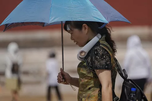 A woman wearing an electric fan and carrying an umbrella visits the Forbidden City on a sweltering day in Beijing, on July 7, 2023. Earlier this week, Beijing reported more than nine straight days with temperatures above 35 degrees Celsius (95 degrees Fahrenheit), a streak unseen since 1961. (AP Photo/Andy Wong, File)