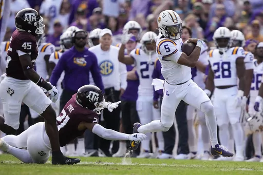 LSU quarterback Jayden Daniels (5) carries past Texas A&M linebacker Taurean York (21) in the first half of an NCAA college football game in Baton Rouge, La., Saturday, Nov. 25, 2023. (AP Photo/Gerald Herbert)
