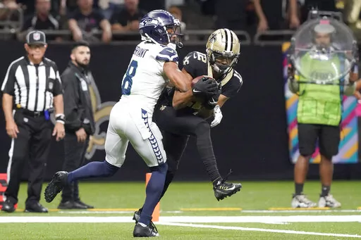 New Orleans Saints wide receiver Chris Olave catches a touchdown pass from quarterback Andy Dalton as Seattle Seahawks cornerback Coby Bryant defends during an NFL football game in New Orleans, Sunday, Oct. 9, 2022. (AP Photo/Gerald Herbert)