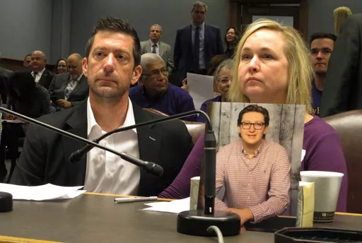 Stephen and Rae Ann Gruver sit in a House committee room behind a photo of their son, 18-year-old Maxwell Gruver, a Louisiana State University freshman who died with a blood-alcohol content six times higher than the legal limit for driving in what authorities say was a hazing incident, in Baton Rouge, La., on March 21, 2018. A jury’s decision that Gruver's family is entitled to $6.1 million for Maxwell's hazing-related alcohol death in 2017 sends a powerful message, the family’s attorney sai