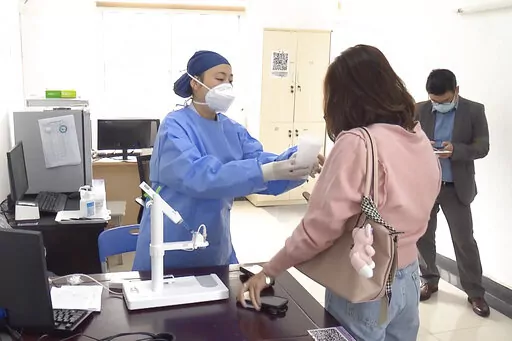 In this photo taken from video released by Shanghai Media Group, a medical worker hands over aerosolised COVID vaccine developed by Chinese biopharmaceutical company CanSino Biologics Inc. in Shanghai on Wednesday, Oct. 26, 2022. The Chinese city of Shanghai started administering the inhalable COVID-19 vaccine on Wednesday in what appears to be a world first. (Shanghai Media Group via AP)
