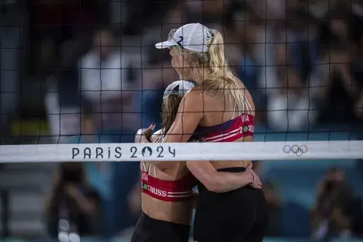 United States' Taryn Kloth and Kristen Nuss celebrate victory in the women's pool B beach volleyball match between USA and Canada at Eiffel Tower Stadium at the 2024 Summer Olympics, Saturday, July 27, 2024, in Paris, France. (AP Photo/Louise Delmotte)