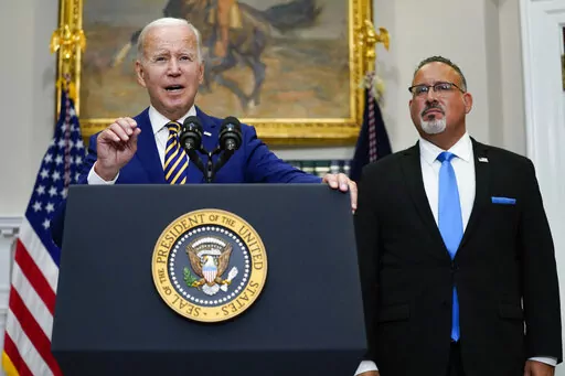President Joe Biden speaks about student loan debt forgiveness in the Roosevelt Room of the White House, on Aug. 24, 2022, in Washington. Education Secretary Miguel Cardona listens at right. The White House is moving forward with a proposal that would lower student debt payments for millions of Americans now and in the future, offering a new route to repay federal loans under far more generous terms. Education Department officials on Tuesday, Jan. 10, 2023, called the new plan a “student loan 