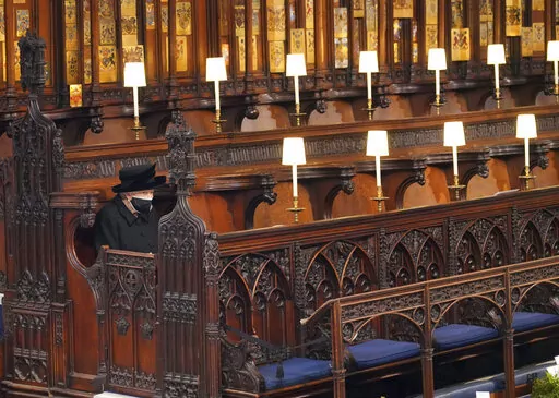 Britain's Queen Elizabeth II sits alone in St. George's Chapel during the funeral of Prince Philip, the man who had been by her side for 73 years, at Windsor Castle, Windsor, England, Saturday April 17, 2021. Boris Johnson's former communications chief has apologized "unreservedly" on Friday for a lockdown-breaching party in Downing Street last year. The Daily Telegraph said Downing Street staff drank, danced and socialized on April 16 last year, the night before the funeral of Prince Philip. Th