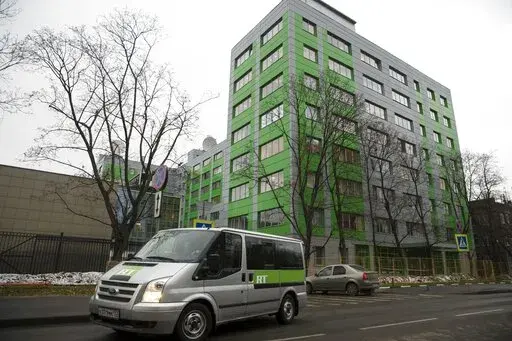 In this file photo taken on Friday, Oct. 27, 2017, a car of Russian state-owned television station RT passes by the company's office in Moscow, Russia. Britain’s communications regulator has revoked the license of Russian-backed broadcaster RT amid investigations of its coverage of the Ukraine war. The regulator, Ofcom, said it a statement that it did not consider RT’s licensee, ANO TV Novosti, to be “fit and proper to hold a U.K. broadcast license.” (AP Photo/Pavel Golovkin, FILE)