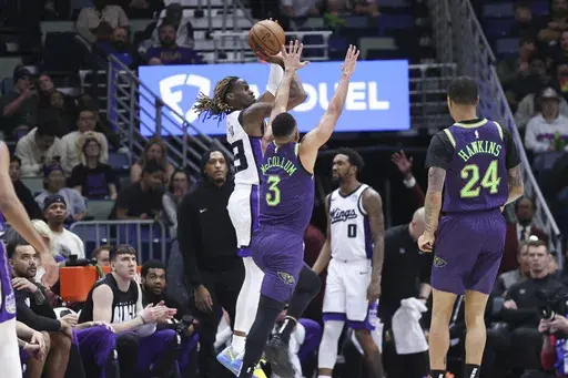 Sacramento Kings guard Keon Ellis (23) shoots a three-pointer over New Orleans Pelicans guard CJ McCollum (3) during the first half of an NBA basketball game in New Orleans, Wednesday, Feb. 12, 2025. (AP Photo/Peter Forest)