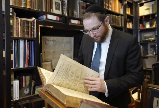 Rabbi Nicky Liss looks through items in a collection belonging to Professor David Latchman of memorabilia related to the history of British Jews, in London, Friday, April 28, 2023. Rabbi Nicky Liss won’t be watching King Charles III’s coronation. He’ll be doing something more important praying for the monarch on the Jewish sabbath. On Saturday, he will join rabbis across Britain in reading a prayer in English and Hebrew that gives thanks for the new king in the name of the “one God who c