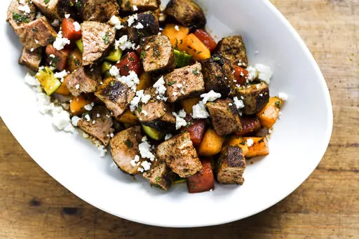 This image released by Milk Street shows a recipe for Chili-rubbed Pork with Cucumber-Melon Salad. (Milk Street via AP)