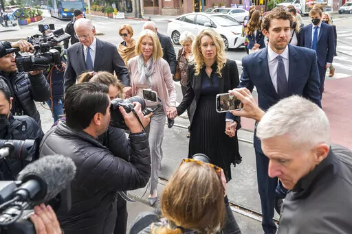 Theranos founder and CEO Elizabeth Holmes, center, walks into federal court with her partner Billy Evans, right, and her parents in San Jose, Calif., Friday, Nov. 18, 2022.  A federal judge will decide whether Holmes should serve a lengthy prison sentence for duping investors and endangering patients while peddling a bogus blood-testing technology. 
 (AP Photo/Nic Coury)