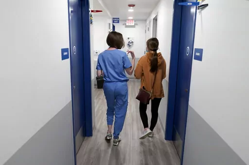 Dr. Elizabeth Brett Daily, left, walks with patient Haley Ruark after providing a medical abortion at a Planned Parenthood clinic Wednesday, Oct. 12, 2022, in Kansas City, Kan. (AP Photo/Charlie Riedel)