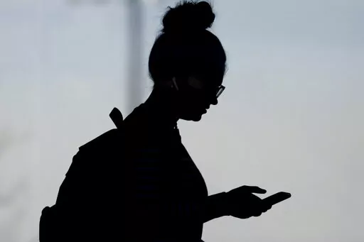 A woman checks her phone in Orem, Utah, on Nov. 14, 2019. A survey of people ages 16 to 40 finds that millennials and Generation Z follow the news, but they aren't that happy with what they're seeing. The study conducted by The Associated Press-NORC Center for Public Affairs Research and the American Press Institute says 79% of people follow news daily, contrary to perceptions that many are tuned out. (AP Photo/Rick Bowmer, File)