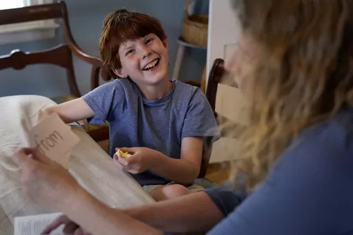 Heather Hollingsworth helps her son Thomas, age 9, work on reading skills after school Thursday, April 20, 2023, at their home in Mission, Kan. (AP Photo/Charlie Riedel)