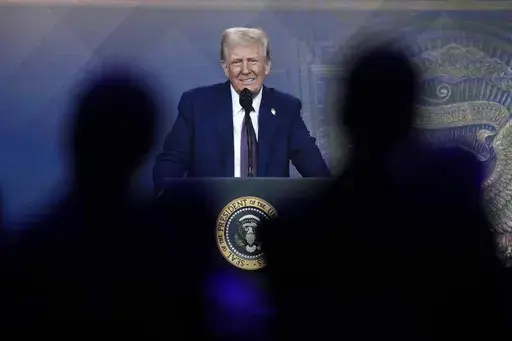 People follow a virtual speech of President Donald Trump at the annual meeting of the World Economic Forum in Davos, Switzerland, Jan. 23, 2025. (AP Photo/Markus Schreiber, File)