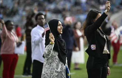 New United States citizens wave American flags during a naturalization ceremony during halftime at an NFL football game between the Jacksonville Jaguars and the New York Jets, Dec. 15, 2024, in Jacksonville, Fla. (AP Photo/Phelan M. Ebenhack, File)