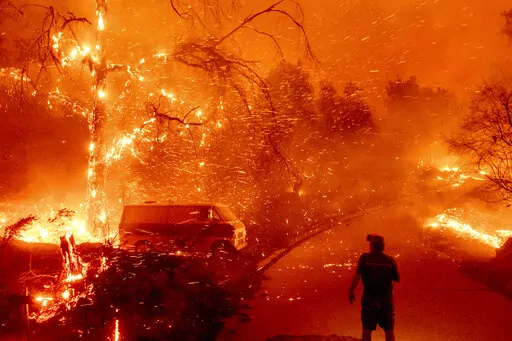 Bruce McDougal watches embers fly over his property as the Bond Fire burns through the Silverado community in Orange County, Calif., on Dec. 3, 2020. The United Nations on Monday, Feb. 28, 2022, released a new report on climate change. (AP Photo/Noah Berger, File)