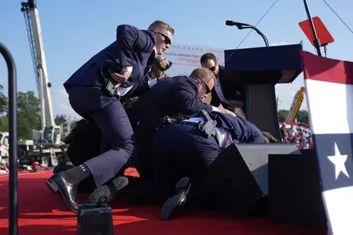 Republican presidential candidate former President Donald Trump is covered by U.S. Secret Service agents at a campaign rally, Saturday, July 13, 2024, in Butler, Pa. Protective details have grown in size, responsibility and technology over more than a century of the Secret Service protecting presidents. When the commander in chief leaves the White House, they're accompanied by a phalanx of Secret Service officers and agents. (AP Photo/Evan Vucci)