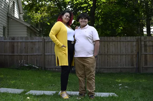 Rousmery Negrón stands with her son at home in Springfield, Mass., on Thursday, Aug. 3, 2023. When in-person school resumed after pandemic closures, Negrón and her son both noticed a change: School seemed less welcoming. Parents were no longer allowed in the building without an appointment, Negrón said. Punishments were more severe. Everyone seemed less tolerant, more angry. Negrón's son even overheard a teacher mocking his learning disabilities, calling him an ugly name. He would end up mis