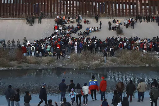 Migrants gather at a crossing into El Paso, Texas, as seen from Ciudad Juarez, Mexico, Tuesday, Dec. 20, 2022. Tensions remained high at the U.S-Mexico border Tuesday amid uncertainty over the future of restrictions on asylum-seekers, with the Biden administration asking the Supreme Court not to lift the limits before Christmas. (AP Photo/Christian Chavez)