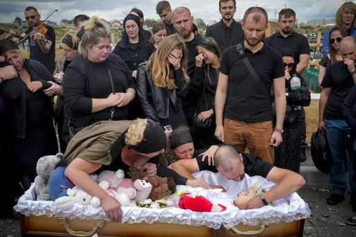 Relatives and friends attend the funeral ceremony for Liza, 4-year-old girl killed by Russian attack, in Vinnytsia, Ukraine, Sunday, July 17, 2022. Wearing a blue denim jacket with flowers, Liza was among 23 people killed, including two boys aged 7 and 8, in Thursday's missile strike in Vinnytsia. Her mother, Iryna Dmytrieva, was among the scores injured. (AP Photo/Efrem Lukatsky)