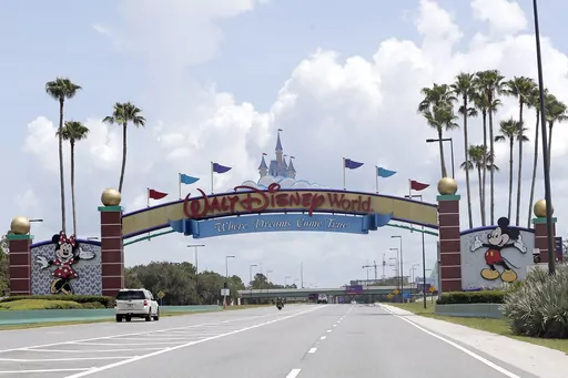 Cars drive under a sign greeting visitors near the entrance to Walt Disney World, July 2, 2020, in Lake Buena Vista, Fla. The first meeting of the new board of Walt Disney World’s government — overhauled by sweeping legislation signed by Republican Gov. Ron DeSantis as an apparent punishment for Disney publicly challenging Florida’s so-called “Don’t Say Gay” bill — dealt with the rote affairs any other municipal government handles. Board members on Wednesday, March 8, 2023, faced c