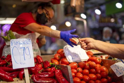 A customer pays for vegetables at the Maravillas market in Madrid, on May 12, 2022. Inflation figures for Europe will be released Friday, July 1, 2022, as Russia's war in Ukraine has worsened the worldwide surge in consumer prices. For months, inflation in the 19 countries that use the euro has risen at the fastest pace since record-keeping for the currency began. (AP Photo/Manu Fernandez, File)