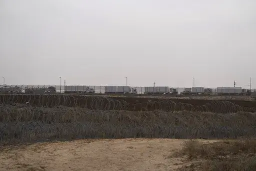 Trucks, carrying humanitarian supplies for the Gaza Strip, wait in line on the Egyptian side, at the Kerem Shalom Crossing border as seen from southern Israel, Thursday, April 25, 2024. A persistent breakdown in law and order is rendering an aid route in south Gaza unusable, the UN and NGOs say, days after Israel's military said it would pause combat there to help aid reach desperate Palestinians. (AP Photo/Leo Correa, File)