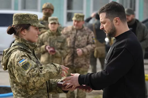 Ukrainian President Volodymyr Zelenskyy presents a medal to a servicewoman in Okhtyrka in the Sumy region of Ukraine, Tuesday March 28, 2023. A team of journalists from The Associated Press traveled with Zelenskyy aboard his train for two nights as he visited troops along the front lines and communities that have been liberated from Russian control. Zelenskyy is hoping his trips keep the public's attention on the war, particularly in parts of Ukraine where life can often appear to have returned 
