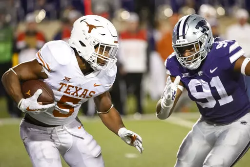 Texas running back Bijan Robinson (5) is pursued by Kansas State defensive end Felix Anudike-Uzomah (91) during the second half of an NCAA college football game on Nov. 5, 2022, in Manhattan, Kan. In an age of “opt-outs” in college football, the best NFL prospects for Alabama and Kansas State are opting in at the Sugar Bowl, on Saturday, Dec. 30, 2022, including Anudike-Uzomah. (AP Photo/Reed Hoffmann, File)