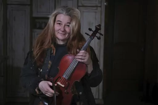 Oksana, 49, who did not want her surname reported, shows a violin she made herself in her small and cold apartment in Bakovka, on the outskirts of Moscow, Russia, Tuesday, Feb. 8, 2022.Oksana's music and colorful instruments lift the spirits of Moscow commuters whose rides are often uncomfortable. (AP Photo/Vitaly Zhiryakov)