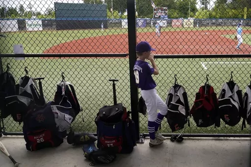 Graham Bacigalupi, of Team Louisiana, watches from the dugout during the DYB, formerly Dixie Youth Baseball, Little League tournament in Ruston, La., Tuesday, Aug. 8, 2023. With climate change driving average global temperatures higher, organizers, players and spectators are having to pay closer attention to the heat. (AP Photo/Gerald Herbert)