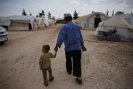 Syrians walk in a camp for internally displaced people in al-Bab, northern Syria, on May 29, 2018. The war in Ukraine helped push the global total of people left internally displaced by conflict or natural disasters to a record high of 71.1 million last year, according to a report released Thursday May 11, 2023. Syria had 6.8 million displaced by conflict after more than a decade of civil war. (AP Photo/Lefteris Pitarakis, File)