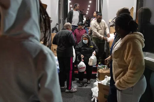 Maria Correa, of Washington, center, who says she is sick with cancer, cannot work, and that things are especially difficult because of the pandemic, accepts a turkey and Thanksgiving trimmings during an annual Thanksgiving food giveaway at The Redeemed Christian Church of God New Wine Assembly, Tuesday, Nov. 22, 2022, in Washington. (AP Photo/Jacquelyn Martin)