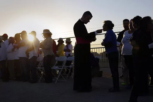 Migrants watching Pope Francis' Mass in Juarez, Mexico, from a levee along the banks of the Rio Grande in El Paso, Texas, take part in Communion, Wednesday, Feb. 17, 2016. According to a poll from The Associated Press-NORC Center for Public Affairs Research conducted in mid-May 2022, only 31% of lay Catholics agree that politicians supporting abortion rights should be denied Communion, while 66% say they be allowed access to the sacrament. (AP Photo/Eric Gay, File)